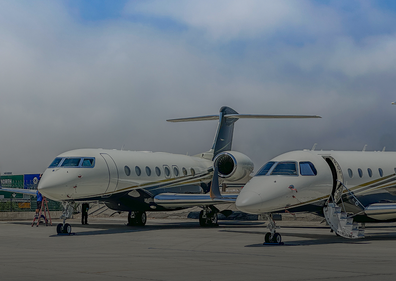 Two private jets parked at airport.