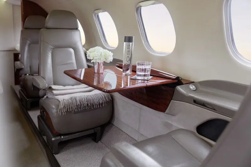 Luxurious private jet interior with leather seats and polished wood table.