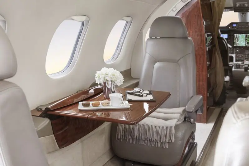 Luxurious leather seat with a fold-out wooden table in a private jet.