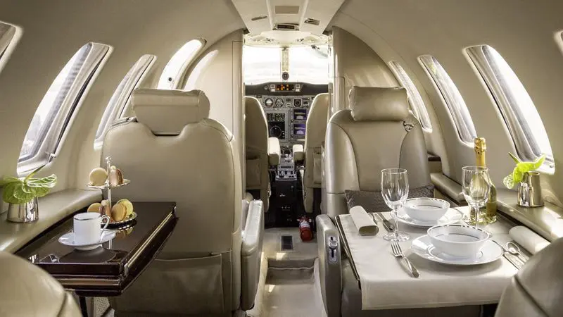Luxurious private jet interior with leather seats and elegant dining setup.