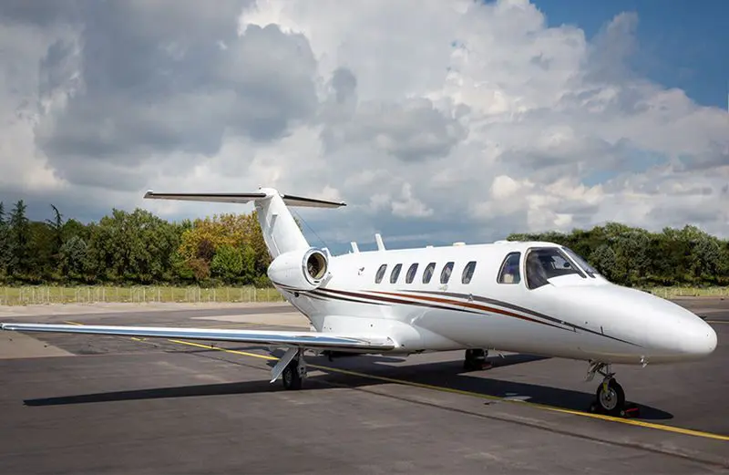 A private jet parked on an airport runway with a cloudy sky.