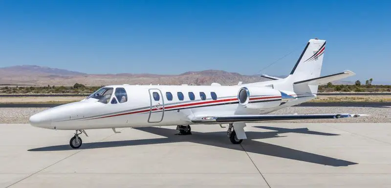 Small private jet parked on a sunny airport tarmac.