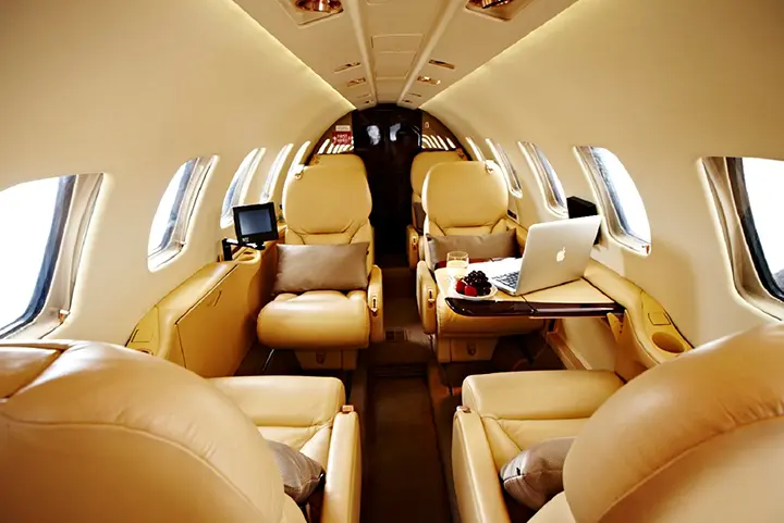 Luxurious private jet interior with beige leather seats and wooden accents.