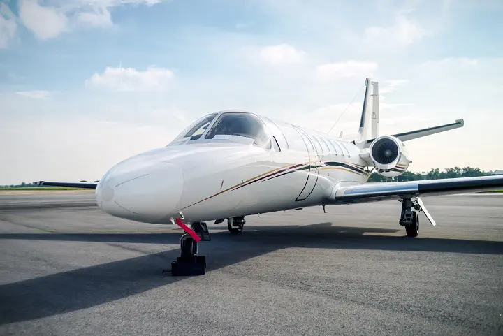 A sleek private jet parked on the runway under a clear sky.