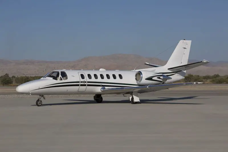 A sleek private jet parked on a runway under a clear sky.