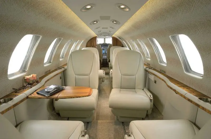 Luxurious interior of a private jet with cream-colored leather seats.