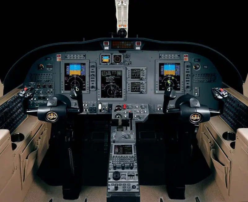 Illuminated airplane cockpit with instrument panels and controls at night.