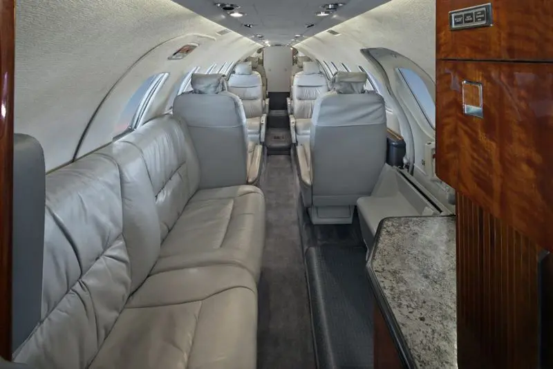 Luxurious interior of a private jet with comfortable leather seats and a marble side table.