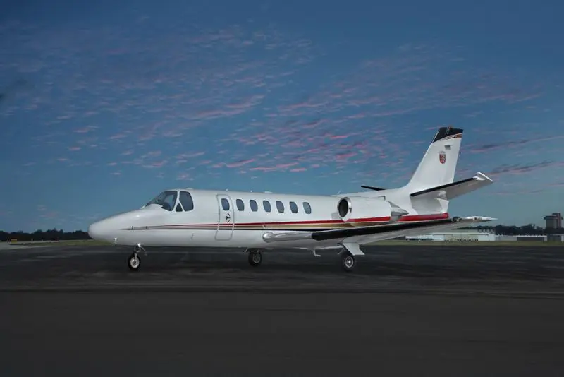 A sleek private jet parked on the runway during dusk.