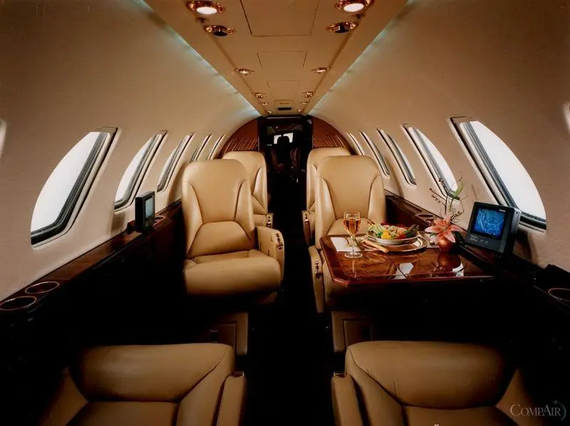 Luxurious interior of a private jet with leather seats and a wooden table.