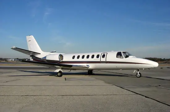 Private jet parked on the runway under clear blue sky.