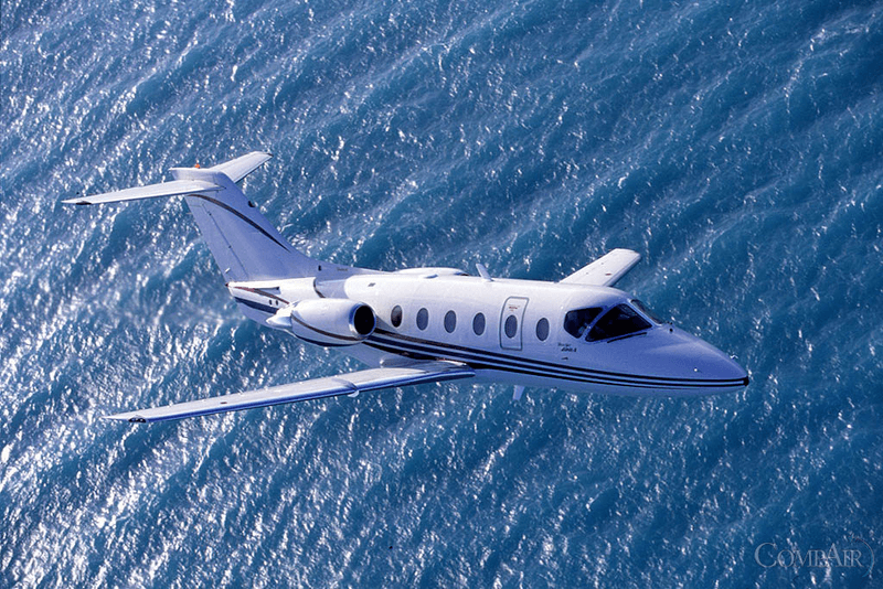 A sleek private jet flying over the ocean.