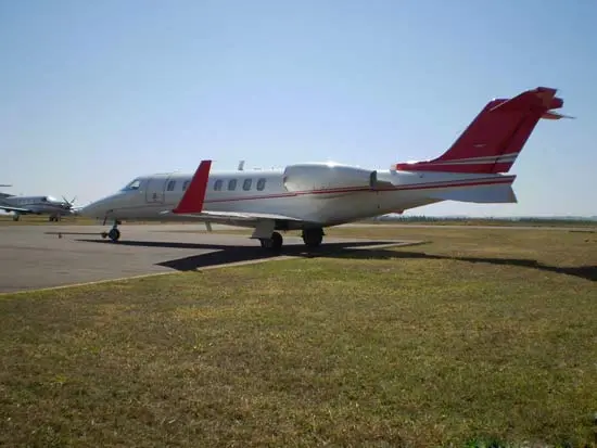 Private jet parked on a grassy airfield under a clear sky.
