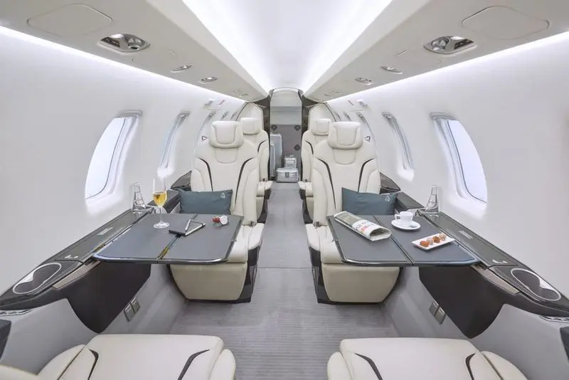 Luxurious private jet interior with spacious leather seats and fold-out tables.