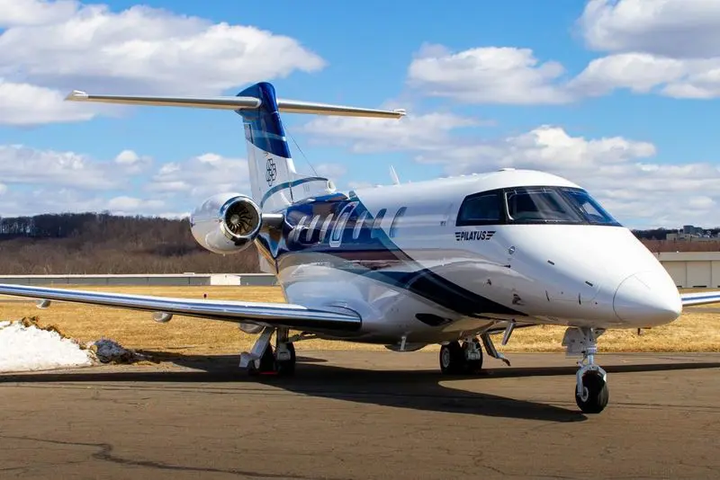 Private jet parked on runway under a blue sky.