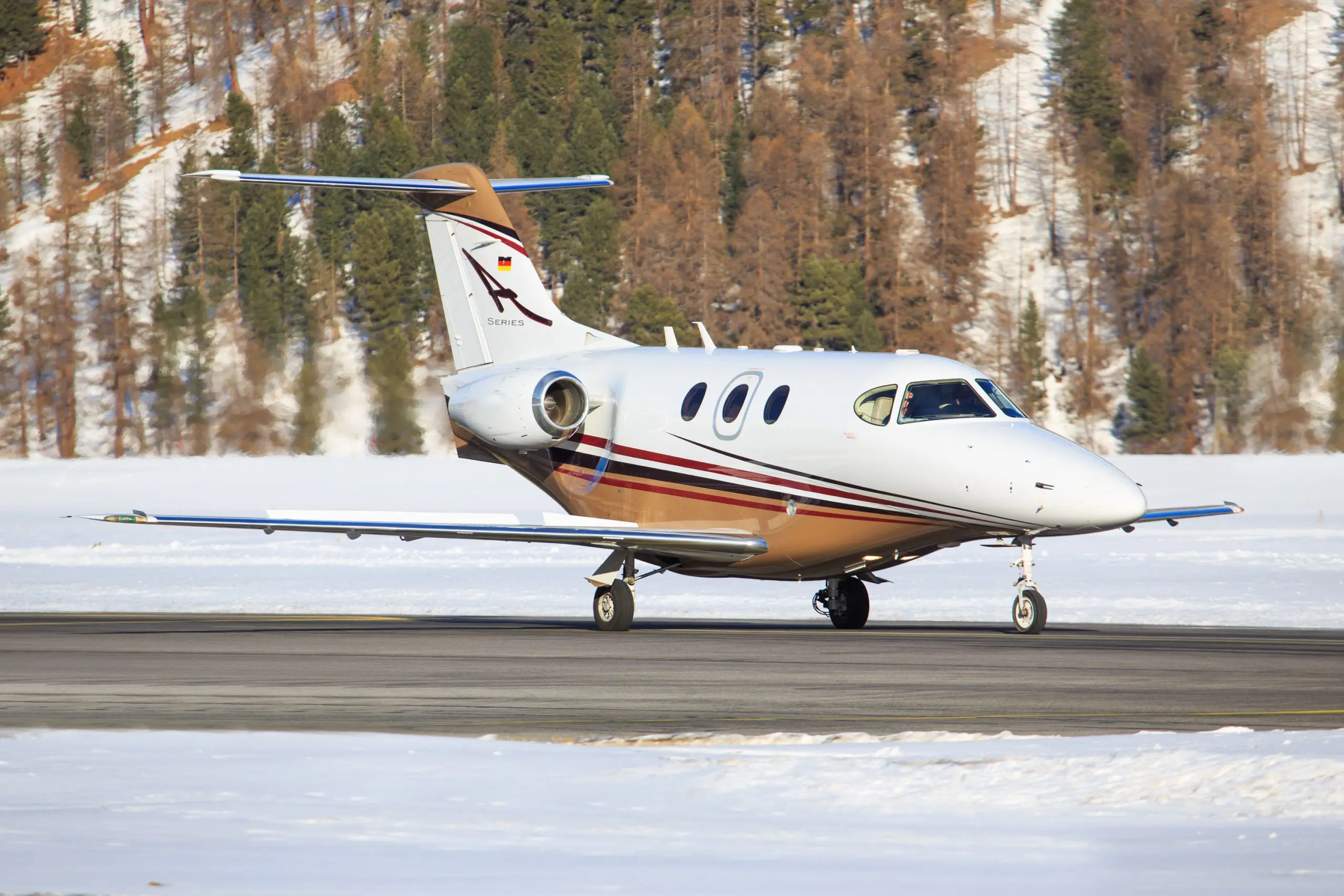 Small private jet taxiing on snowy runway.