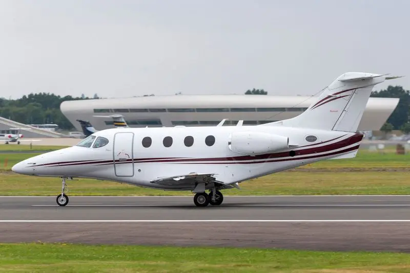 A sleek private jet taxiing on a runway under a clear sky.