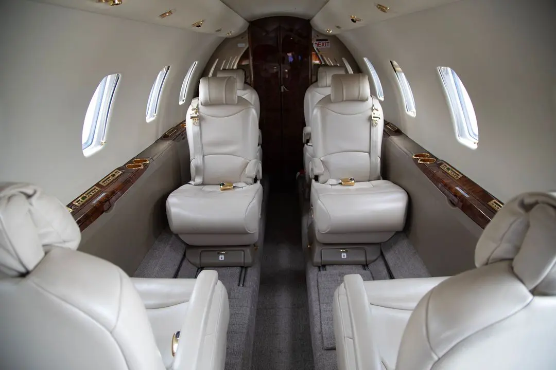 Luxurious interior of a private jet with cream leather seats.