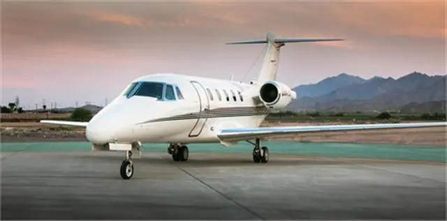 A private jet parked on an airport runway at sunset.