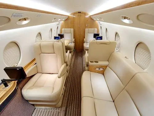 Luxurious beige leather seating inside a private jet cabin.