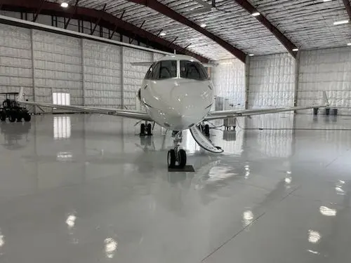 Private jet parked inside a spacious hangar with polished floors.
