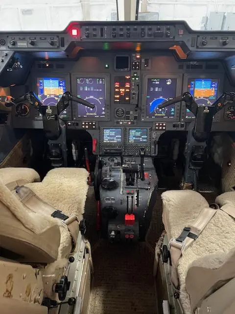Interior view of an airplane cockpit with two pilot seats and control panels.