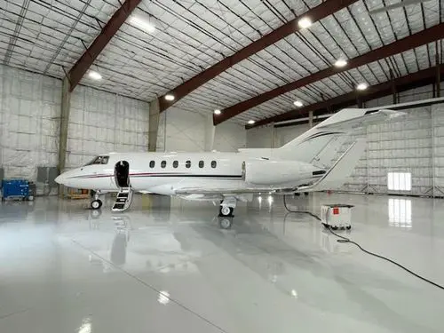 Private jet parked inside a spacious, well-lit aircraft hangar.