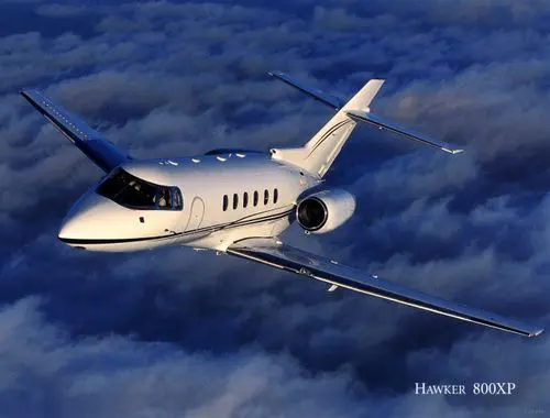 A private jet flying above the clouds during sunset.