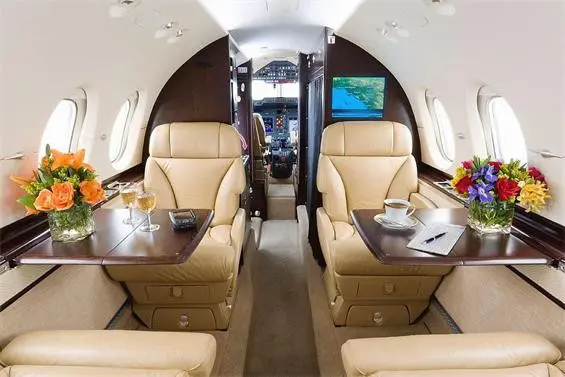 Luxurious private jet interior with leather seats and wooden tables.
