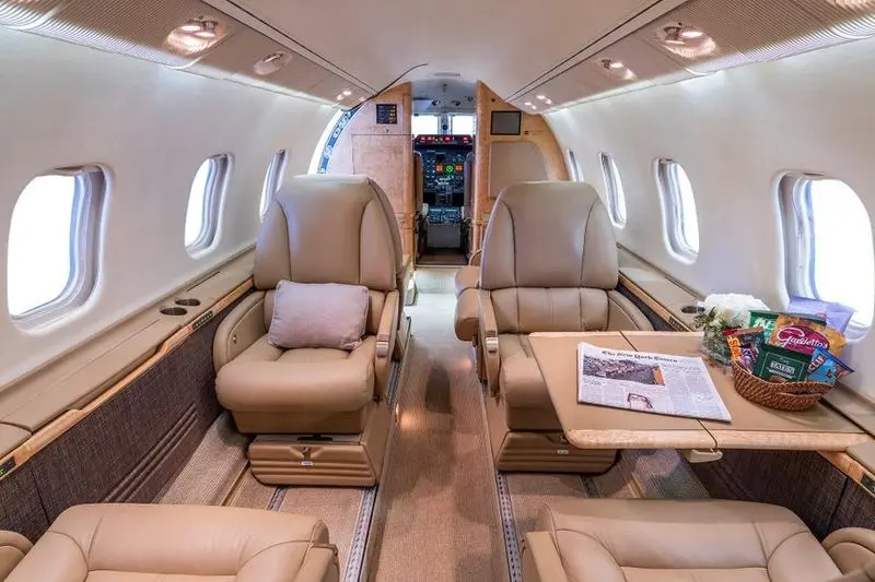 Luxurious interior of a private jet with beige leather seats.