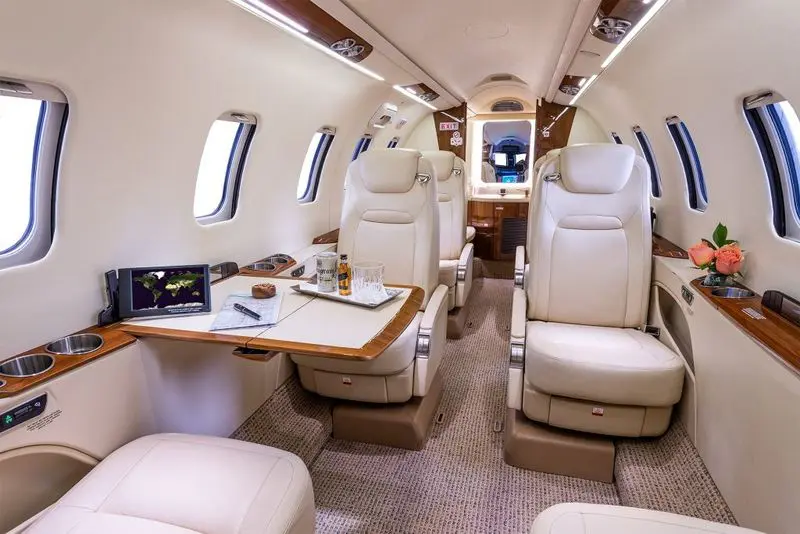 Luxurious interior of a private jet with spacious leather seats and a wooden table.