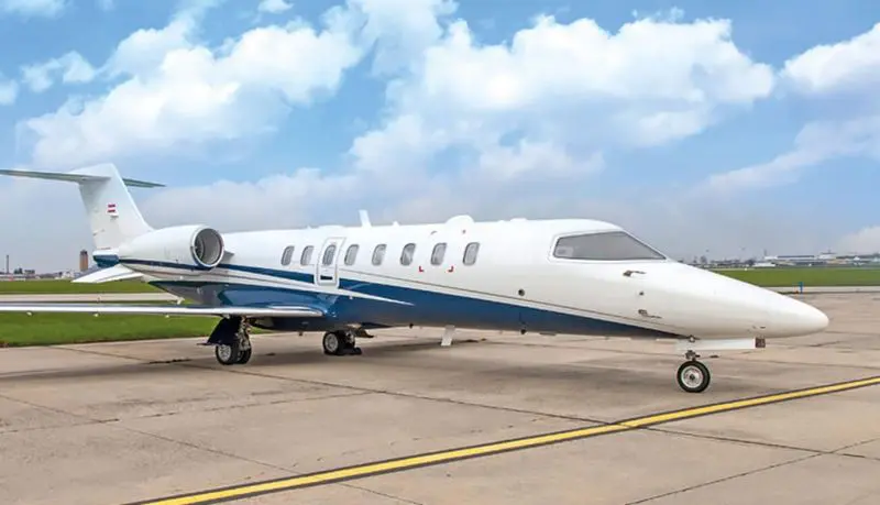A sleek private jet parked on a runway under a blue sky.