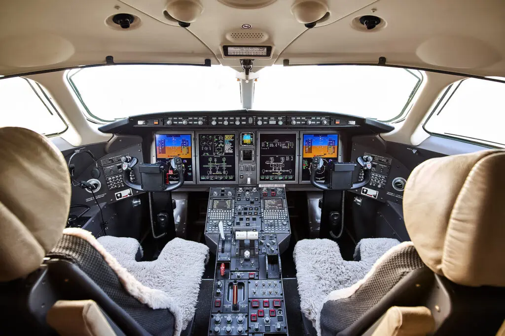 Interior view of an airplane cockpit with controls and displays.