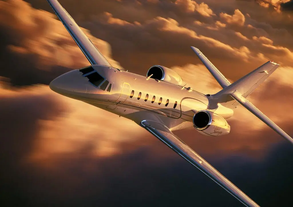 Private jet flying through dramatic sunset skies.