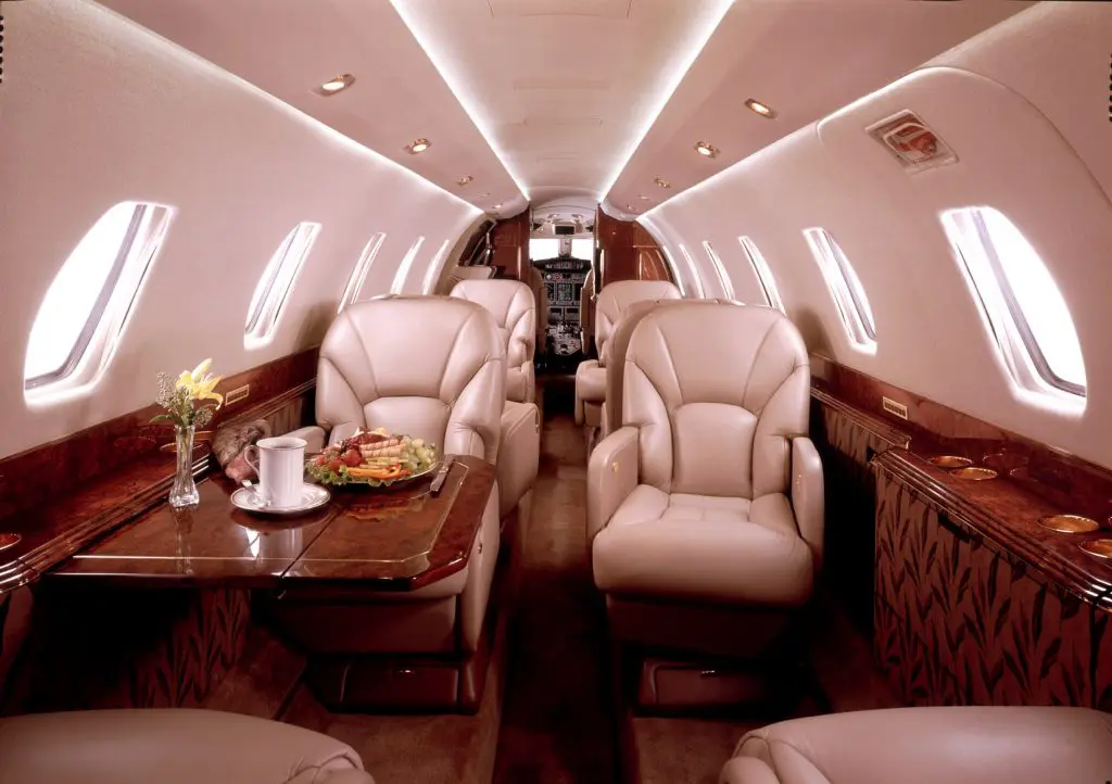 Luxurious private jet interior with plush leather seats and wood accents.
