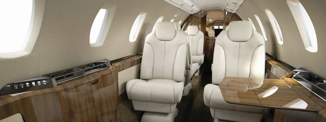 Luxurious cream leather seats inside a private jet cabin.
