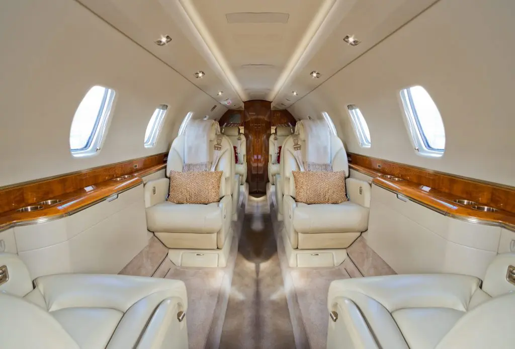 Luxurious private jet interior with spacious leather seats and wooden accents.