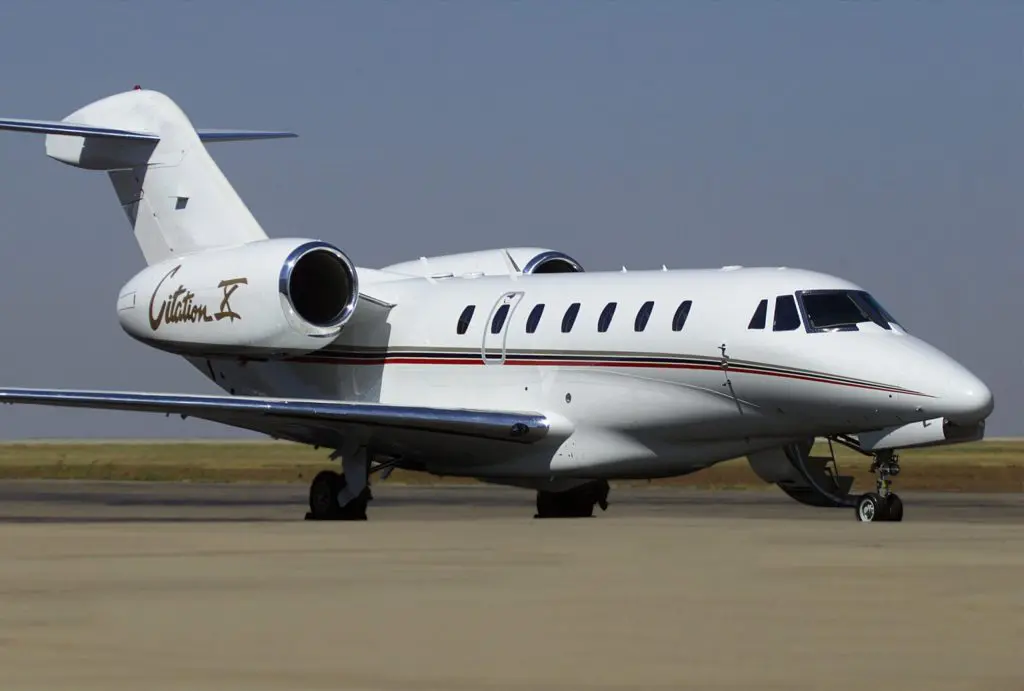 Private jet parked on an airport runway under clear sky.