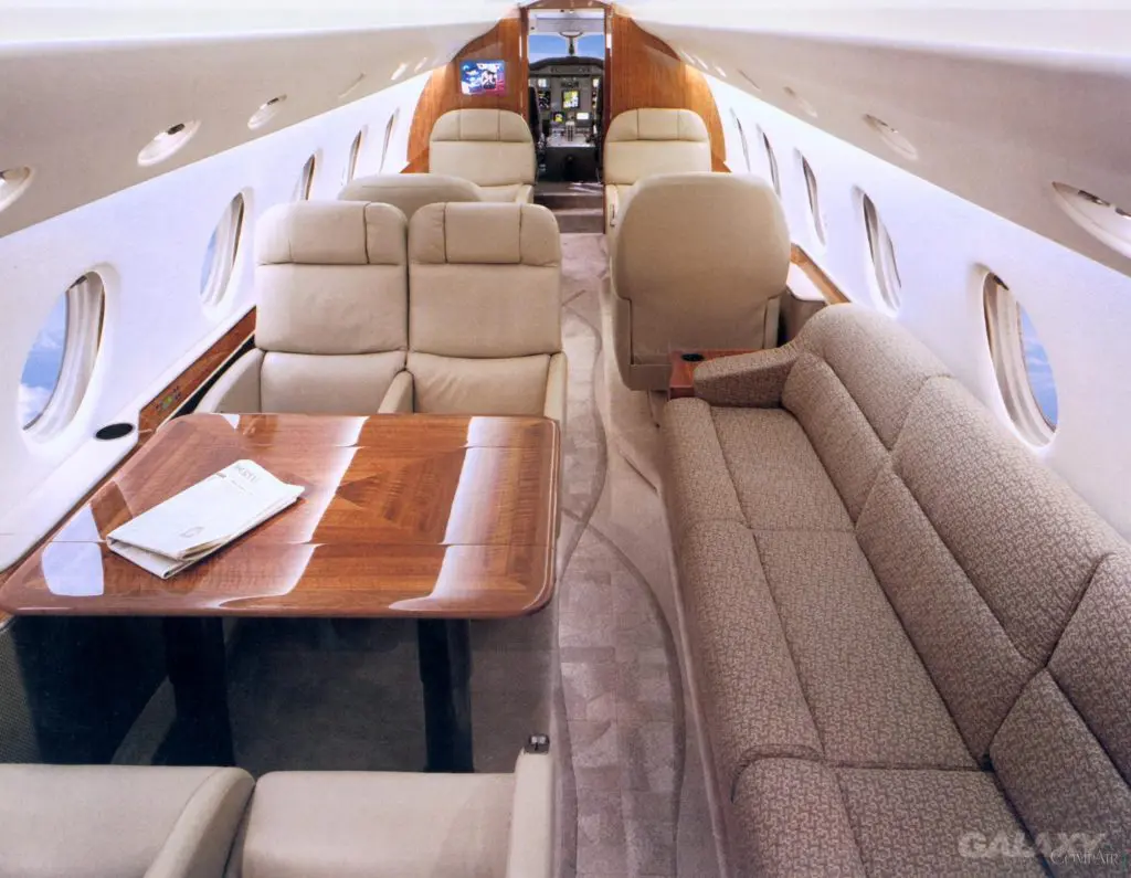 Luxurious interior of a private jet with plush seating and wooden table.