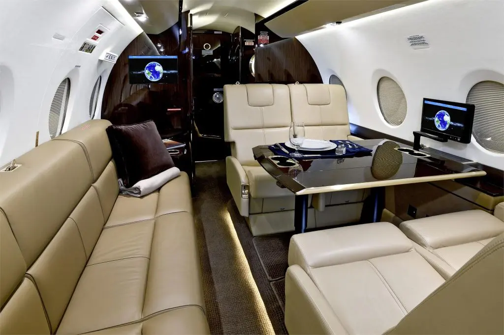 Luxurious private jet interior with cream leather seating and modern amenities.