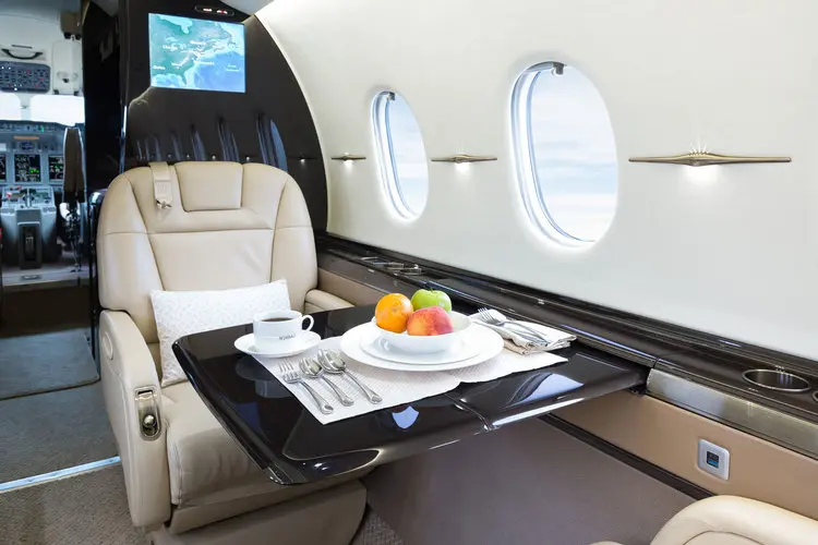 Luxurious airplane interior with a fruit platter on a fold-out table.