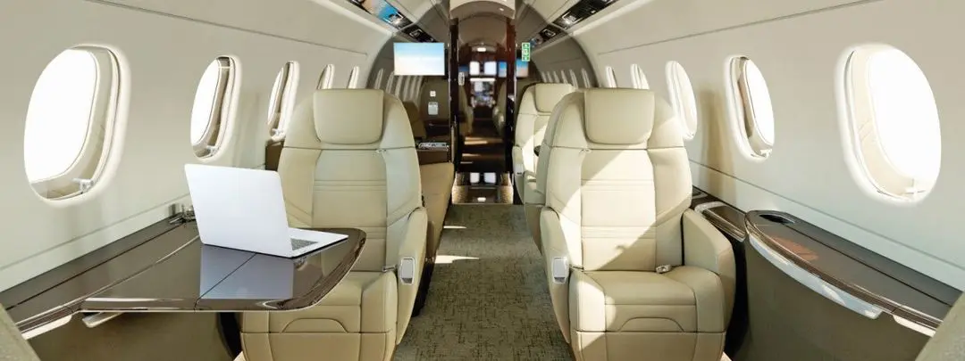 Luxurious beige leather seats inside a private jet cabin.