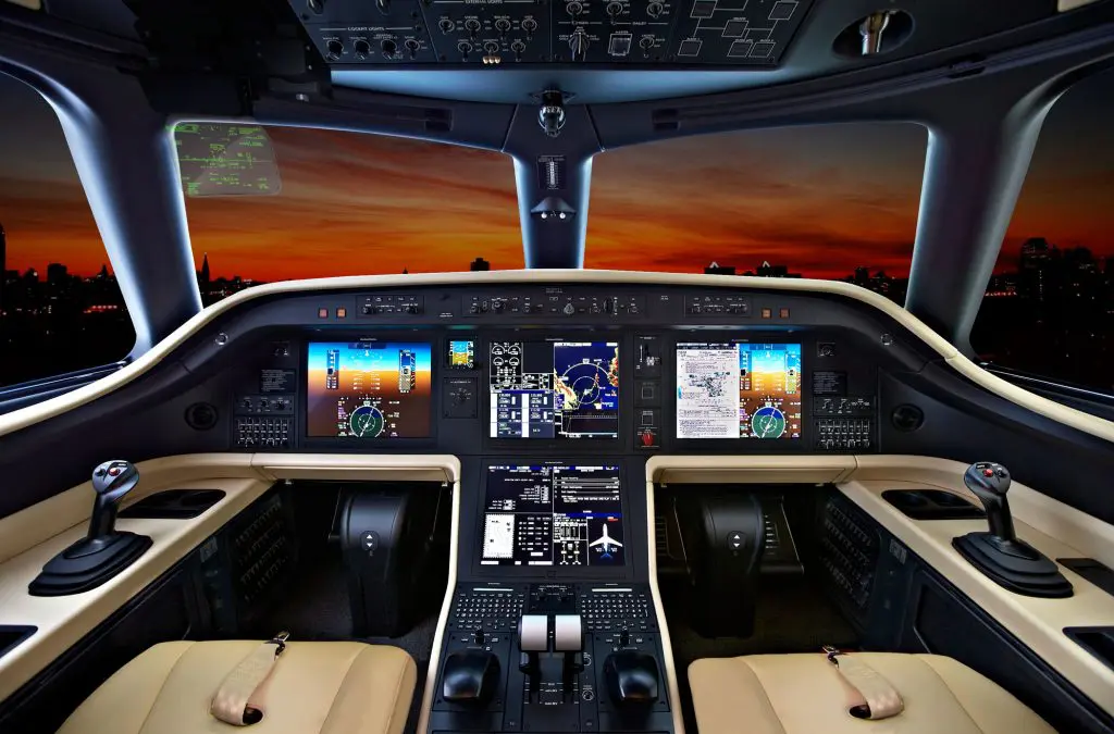 Cockpit view of an airplane at sunset with illuminated controls.