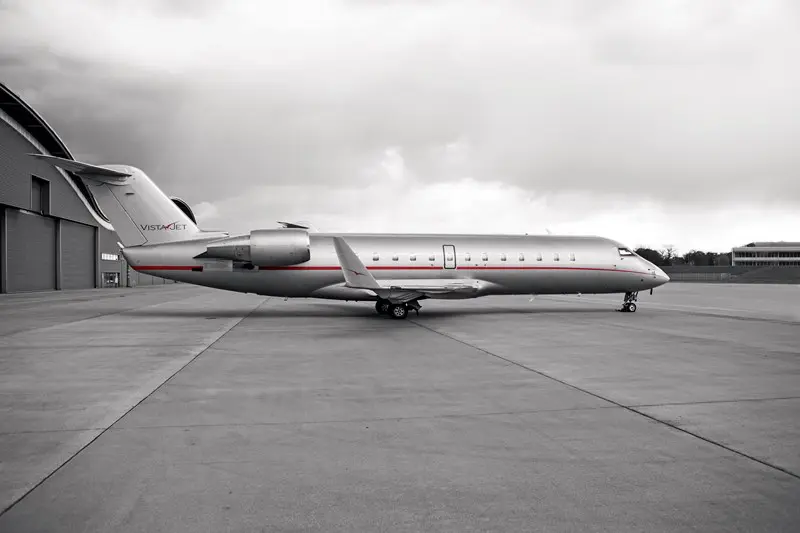 A sleek private jet parked on a runway under a cloudy sky.
