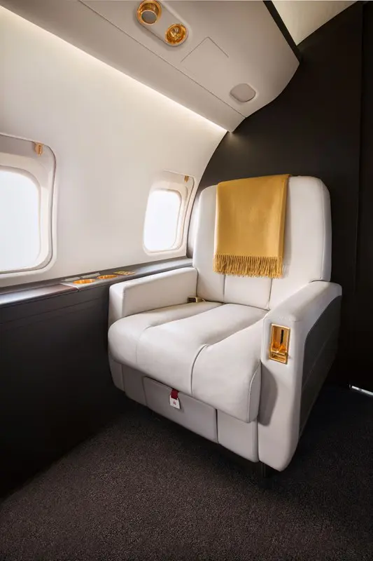 Luxurious airplane seat with a cozy yellow blanket.