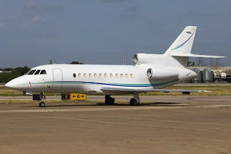 A private jet parked on an airport runway under a clear sky.