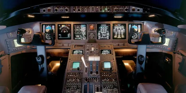 Space shuttle cockpit with illuminated controls and displays.