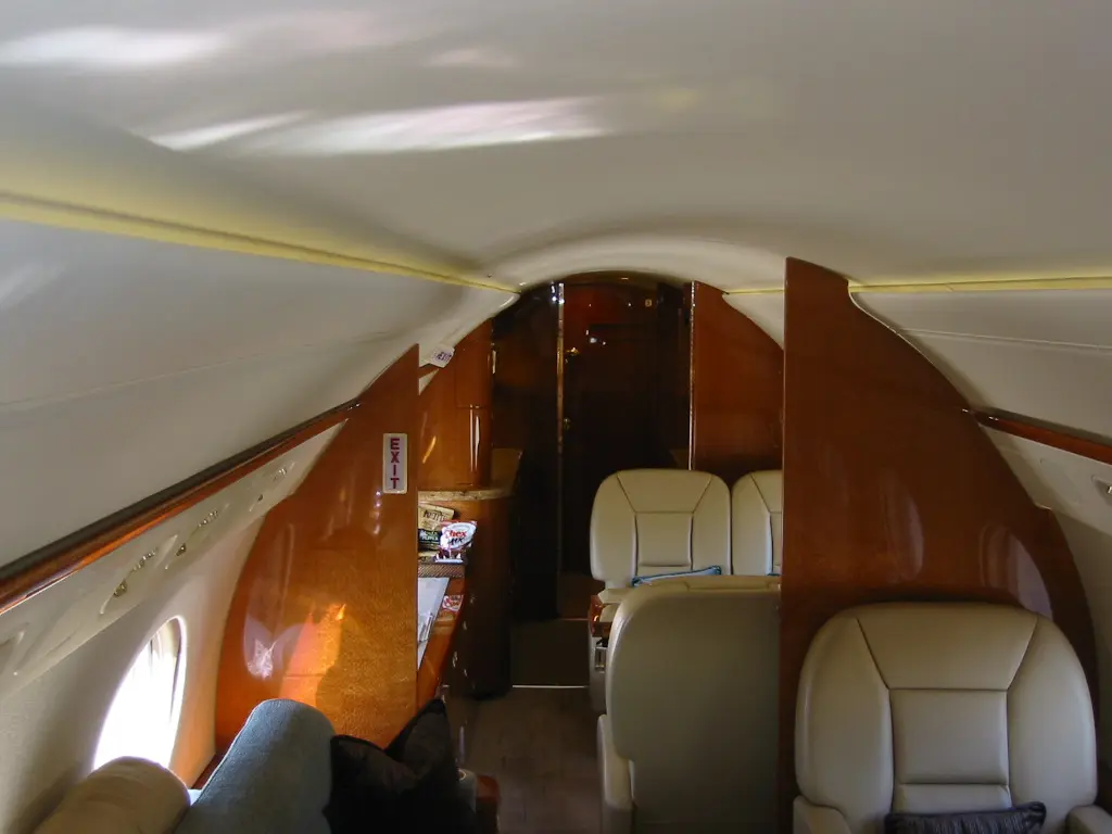 Interior of a private jet with wooden paneling and leather seats.