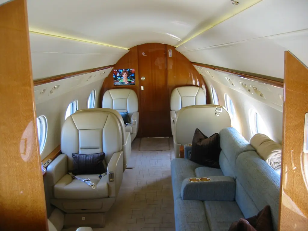 Luxurious private jet interior with leather seats and wood paneling.