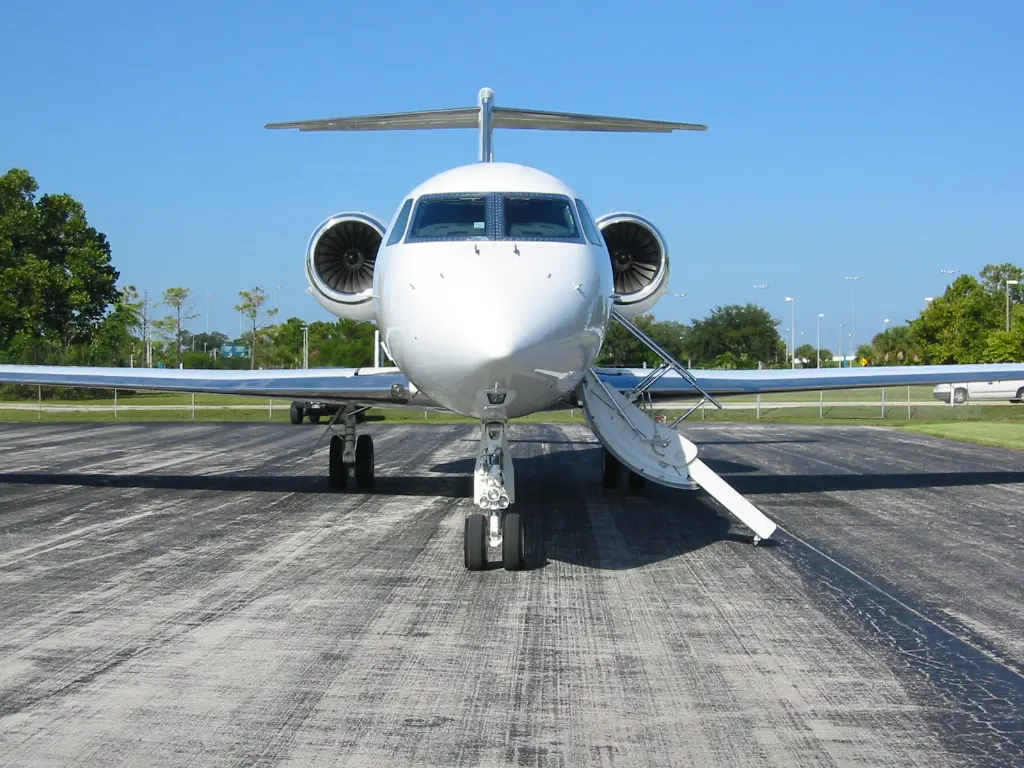Private jet parked on a sunny runway with door open.